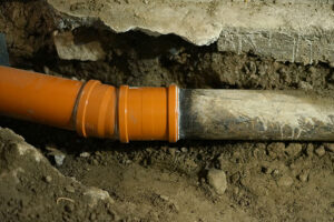 A sewer line under property in Springfield, IL that has been repaired with an orange pipe due to a leak.